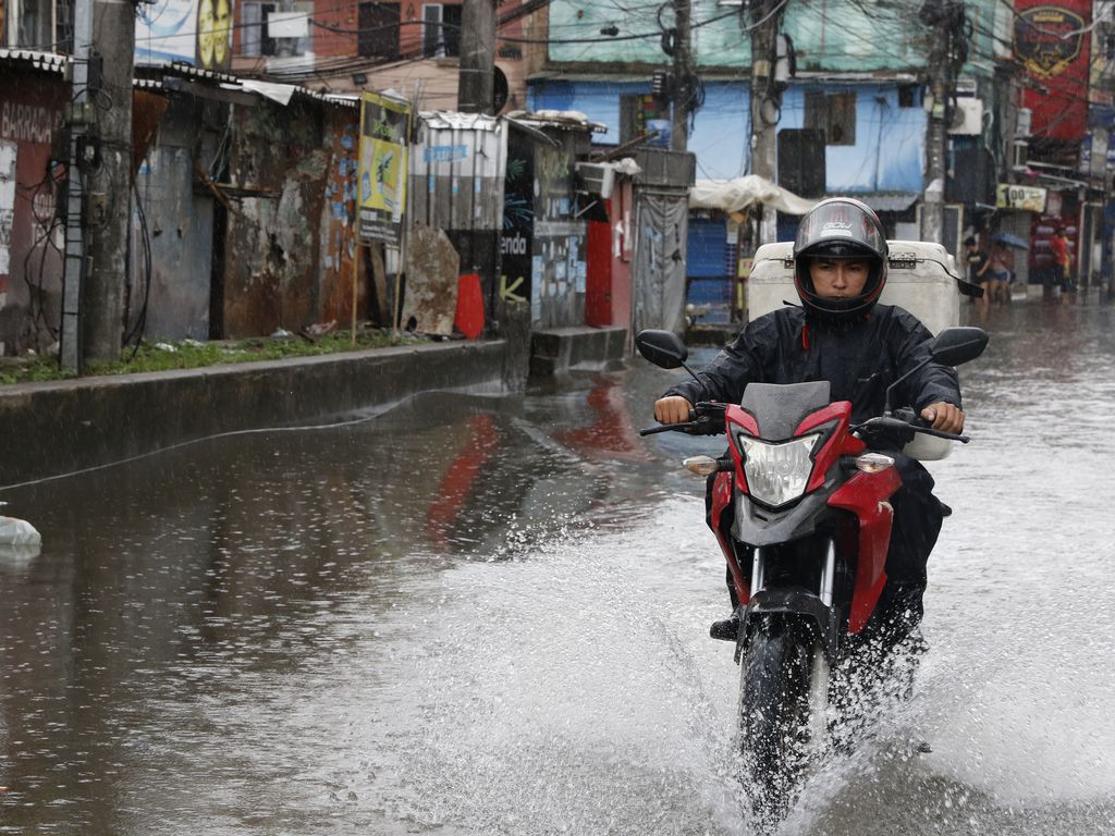 homem atravessa área de enchente com motocicleta
