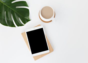 planta, tablet branco e xícara de café sobre superfície branca