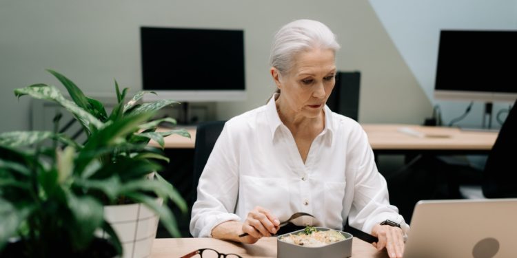 Mulher branca grisalha trabalha em mesa com computador; Mulheres no mercado de trabalho, sobretudo as mais velhas, devem ter apoio das empresas para conciliar a profissão com qualidade de vida, diz pesquisa da FGV