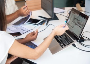 mulher branca aponta para gráfico na tela de computador