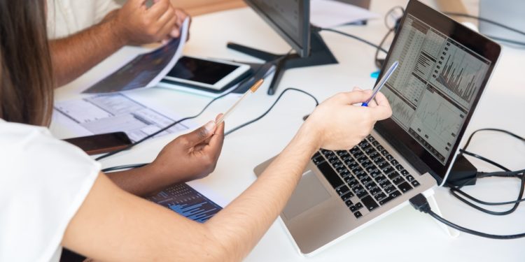 mulher branca aponta para gráfico na tela de computador