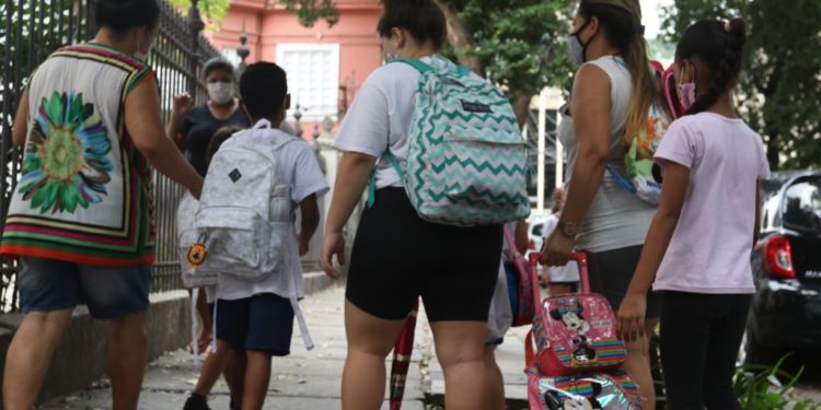 adultas acompanham crianças com uniformes escolares e mochilas a caminho da escola; A política de creches brasileira é um exemplo de ação pública baseada na transversalidade de gênero, pois considera a divisão sexual do trabalho, diz estudo da FGV.