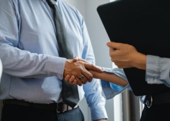 homem e mulher apertam mãos em ambiente de trabalho