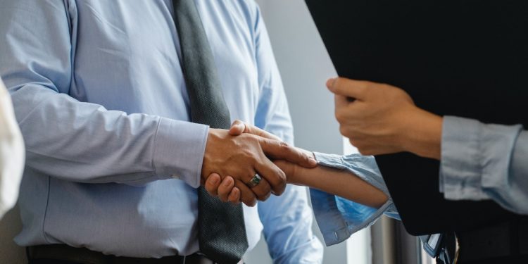 homem e mulher apertam mãos em ambiente de trabalho