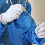 profissional da saúde com luvas e avental azul manueia teste swab