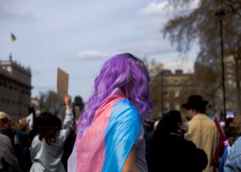 de costas, pessoa com cabexo roxo usa bandeira trans; além de desafios na inclusão de pessoas transgênero no mercado de trabalho, pode haver hostilidade contra aquelas que já estão empregadas, diz estudo da FGV