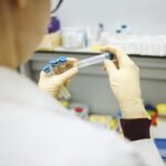 cientista com jaleco branco manipula amostras em laboratório
