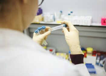 cientista com jaleco branco manipula amostras em laboratório