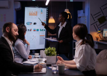 Líder em reunião de equipe em frente a monitor com infográficos
